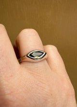 Load image into Gallery viewer, Ring with a green gemstone on a finger against a brown background