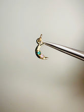 Load image into Gallery viewer, Gold moon-shaped pendant with gemstones held by tweezers against a neutral background
